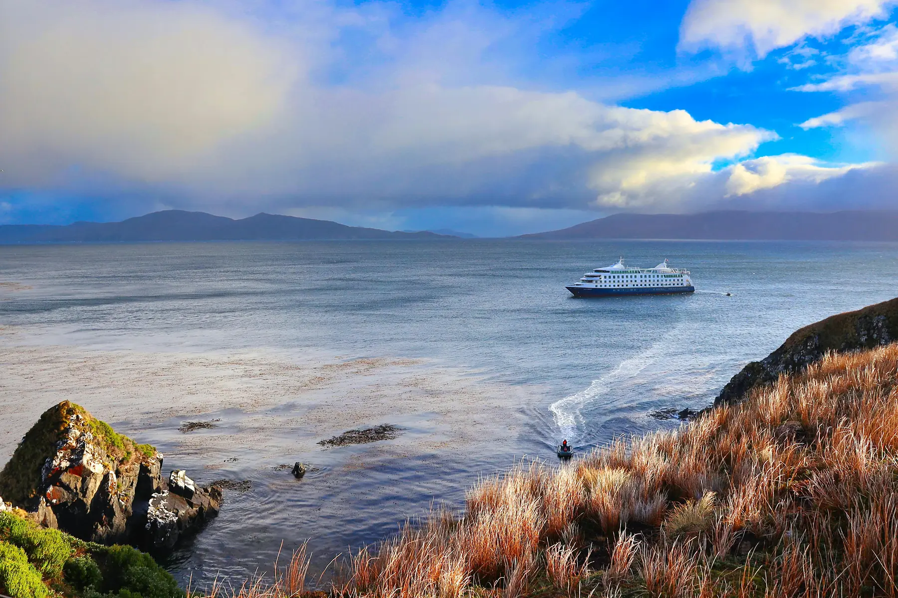 A Zodiac boat from an expedition cruise approaching a remote Patagonian shoreline.