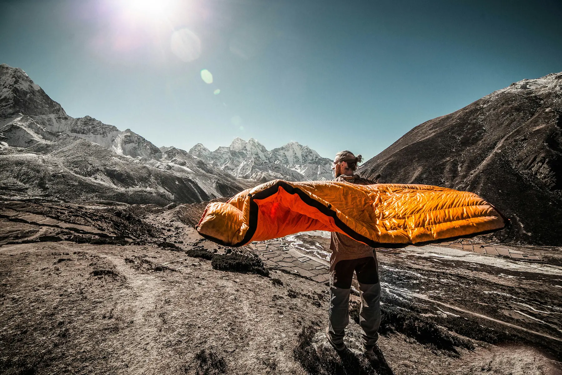 A sleeping bag compressed into a stuff sack beside trekking gear for a Patagonia expedition.